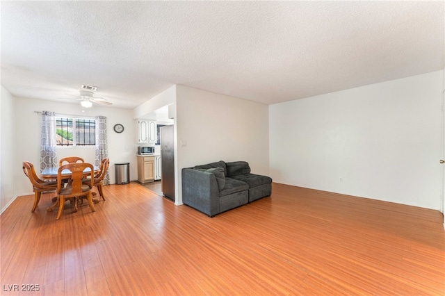 4687 Monterey Cir Unit 1, Las Vegas, NV 89169 - living area with a textured ceiling, light wood-type flooring, visible vents, and ceiling fan