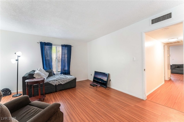 4687 Monterey Cir Unit 1, Las Vegas, NV 89169 - living area featuring a textured ceiling, wood finished floors, visible vents, and baseboards