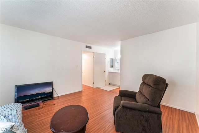 4687 Monterey Cir Unit 1, Las Vegas, NV 89169 - living room featuring a textured ceiling, light wood-style flooring, visible vents, and baseboards