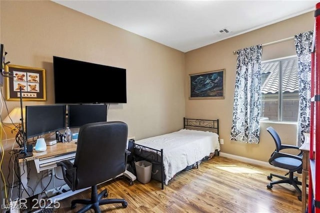bedroom with visible vents, baseboards, and wood finished floors