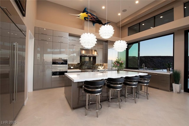 661 Dragon Peak Dr, Henderson, NV 89012 - kitchen with under cabinet range hood, a kitchen bar, modern cabinets, and appliances with stainless steel finishes