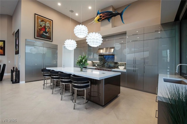 661 Dragon Peak Dr, Henderson, NV 89012 - kitchen featuring a sink, a breakfast bar area, under cabinet range hood, a high ceiling, and modern cabinets