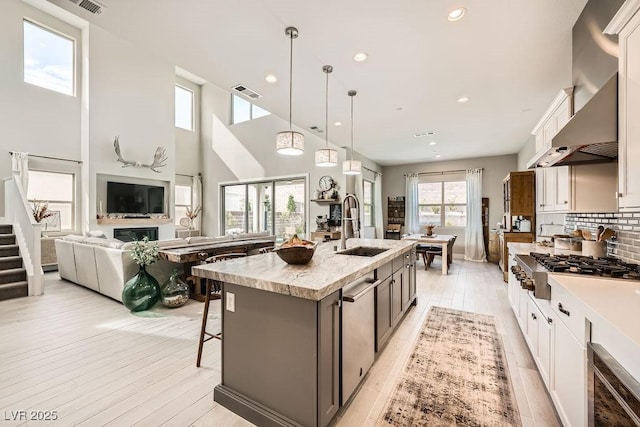 kitchen with a sink, light wood-style flooring, stainless steel appliances, a kitchen bar, and visible vents