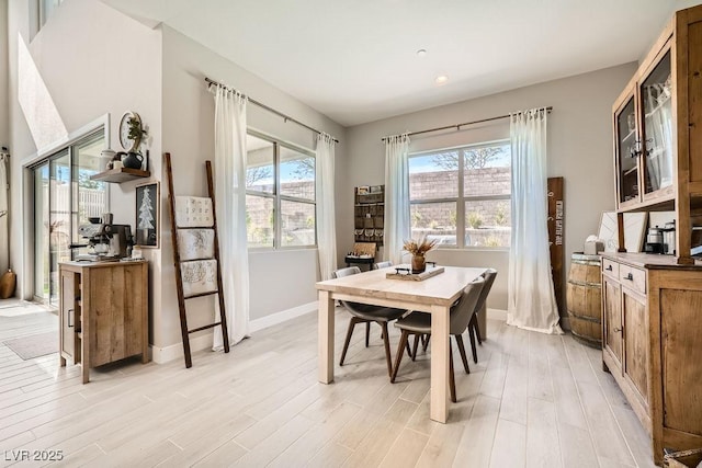 dining room featuring recessed lighting, baseboards, plenty of natural light, and light wood-type flooring