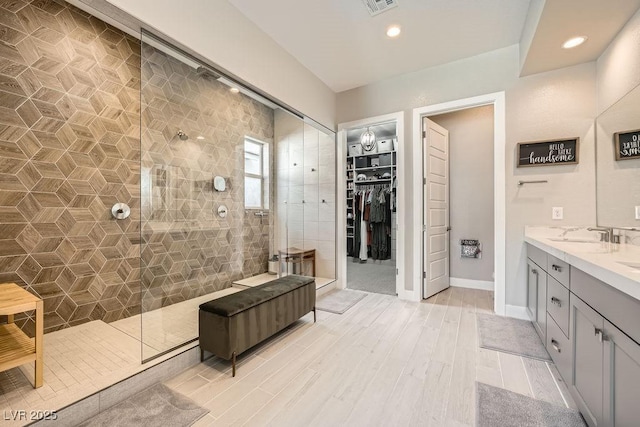 full bath with vanity, wood finished floors, recessed lighting, a walk in shower, and a spacious closet