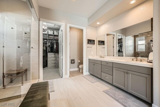 bathroom with a sink, double vanity, toilet, and tiled shower