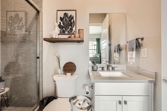 full bathroom with vanity, toilet, a textured wall, and a stall shower