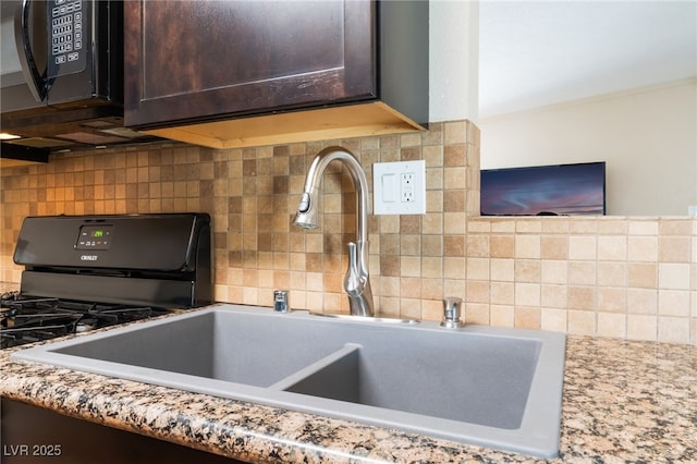 1615 Palora Ave, Las Vegas, NV 89169 - kitchen view of a sink, dark brown cabinetry, backsplash, black microwave, and light stone countertops