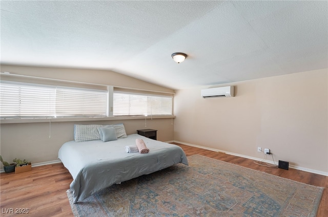 1615 Palora Ave, Las Vegas, NV 89169 - bedroom featuring an AC wall unit, lofted ceiling, wood finished floors, baseboards, and a textured ceiling
