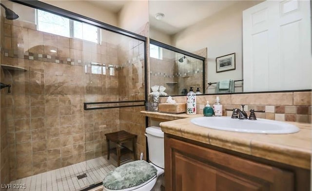 full bathroom with a stall shower, vanity, and toilet