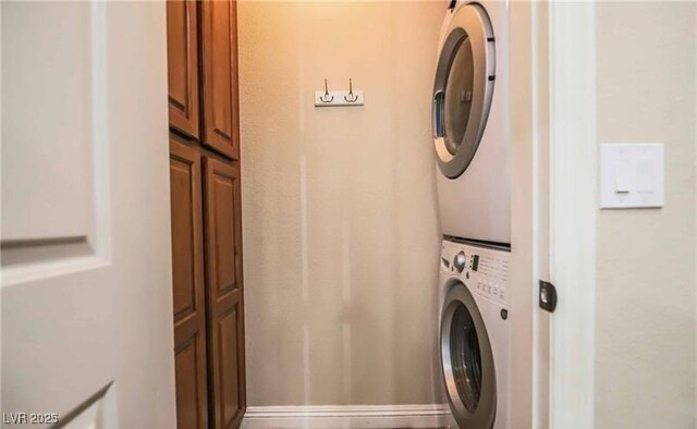 clothes washing area with cabinet space and stacked washing maching and dryer