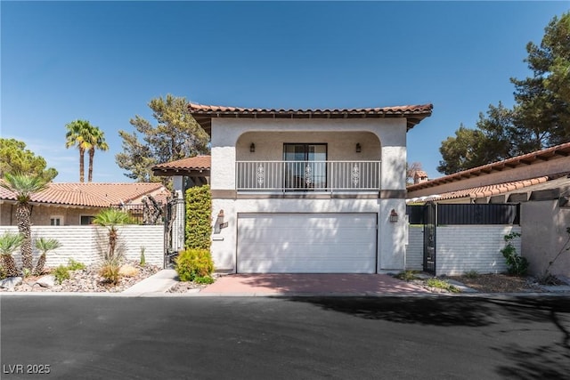 mediterranean / spanish-style home featuring an attached garage, stucco siding, a balcony, a tiled roof, and fence