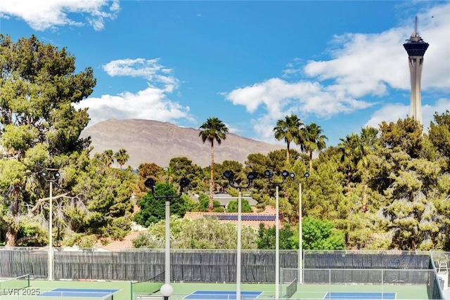 view of tennis court with a mountain view and fence