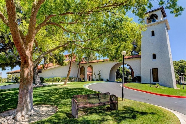 mediterranean / spanish house featuring stucco siding, a front lawn, and curved driveway