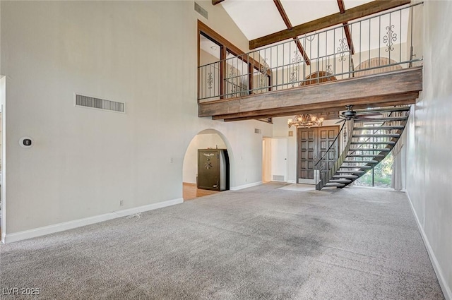 unfurnished living room with high vaulted ceiling, stairs, baseboards, arched walkways, and carpet floors