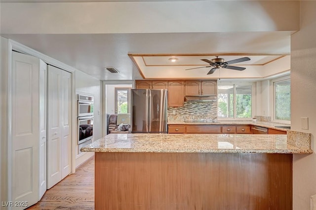 kitchen featuring appliances with stainless steel finishes, a raised ceiling, plenty of natural light, and ceiling fan