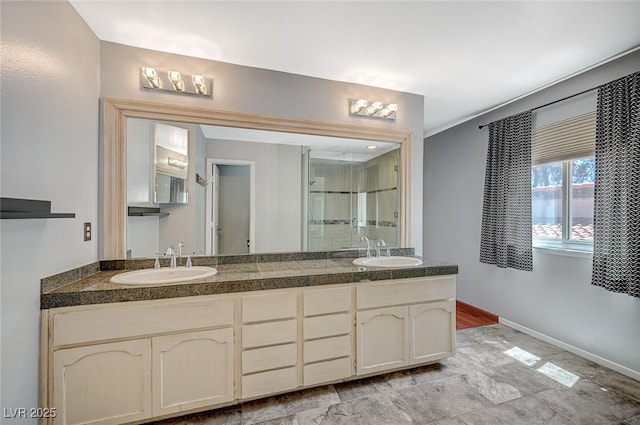 bathroom featuring a stall shower, double vanity, and baseboards