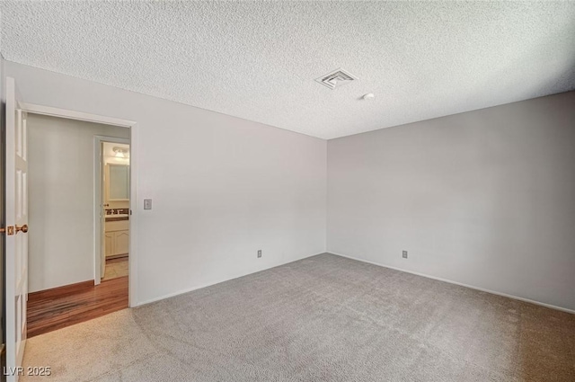 spare room featuring carpet floors and a textured ceiling