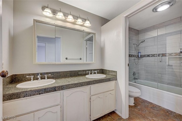 bathroom with toilet, combined bath / shower with glass door, and double vanity