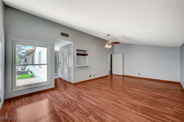 unfurnished living room with vaulted ceiling, a textured ceiling, ceiling fan, wood finished floors, and baseboards