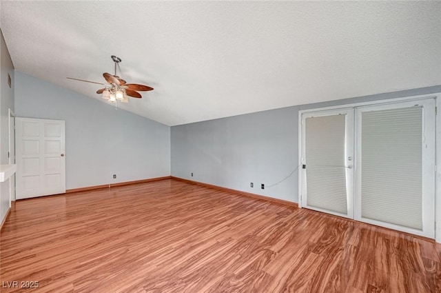 unfurnished living room featuring lofted ceiling, ceiling fan, light wood-style floors, baseboards, and a textured ceiling