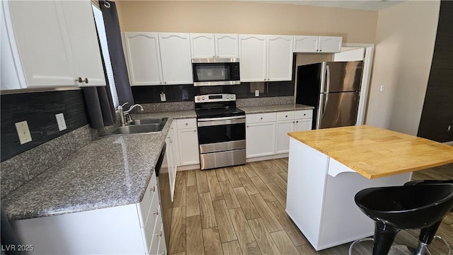83 Rock Run St, Las Vegas, NV 89148 - kitchen featuring white cabinets, stainless steel appliances, a sink, light wood-type flooring, and backsplash
