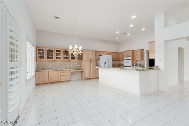 kitchen featuring white appliances, wallpapered walls, backsplash, visible vents, and glass insert cabinets