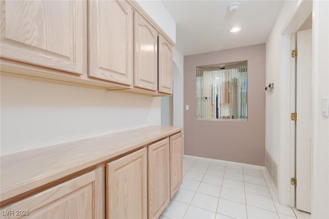 corridor featuring recessed lighting, baseboards, and light tile patterned floors