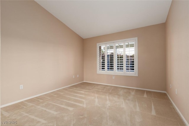 carpeted spare room featuring baseboards and lofted ceiling