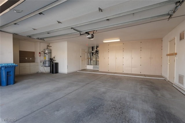 garage with visible vents, a garage door opener, and secured water heater