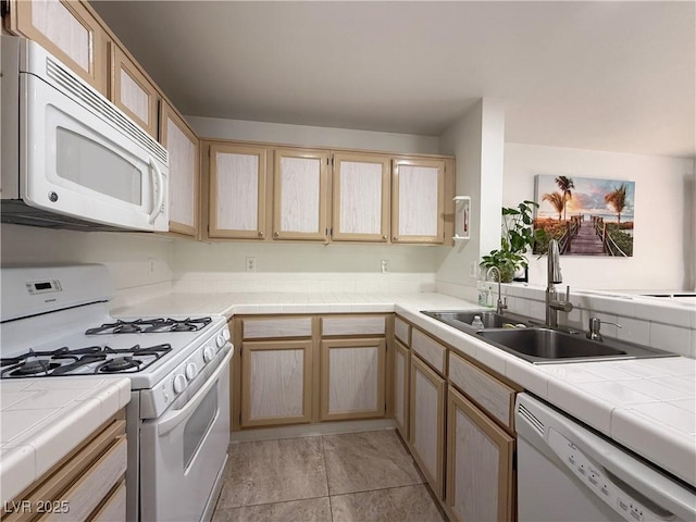 kitchen with white appliances, tile countertops, a sink, and light brown cabinets