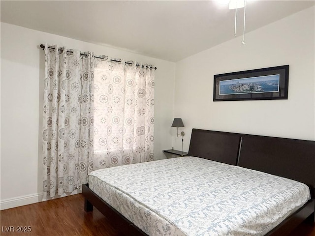 bedroom with baseboards, wood finished floors, and lofted ceiling