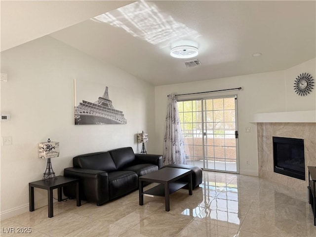 living room featuring baseboards, visible vents, light tile patterned floors, and a fireplace