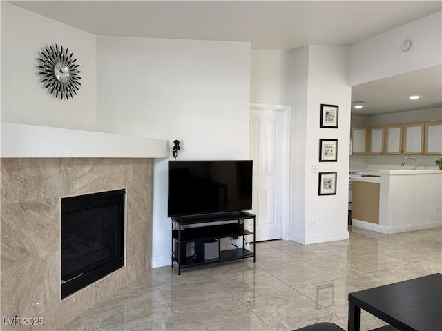 living area with a tiled fireplace, recessed lighting, marble finish floor, and baseboards
