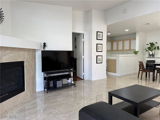 living room with a tiled fireplace, baseboards, recessed lighting, and marble finish floor