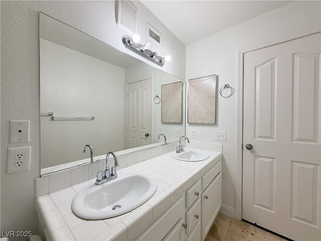 bathroom with double vanity, visible vents, and a sink