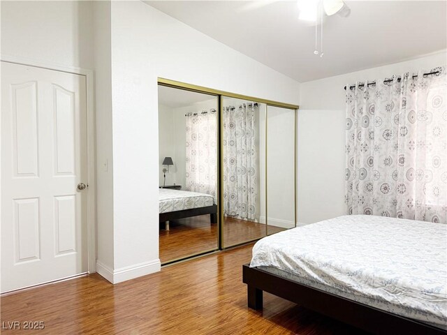 bedroom featuring baseboards, ceiling fan, wood finished floors, and a closet