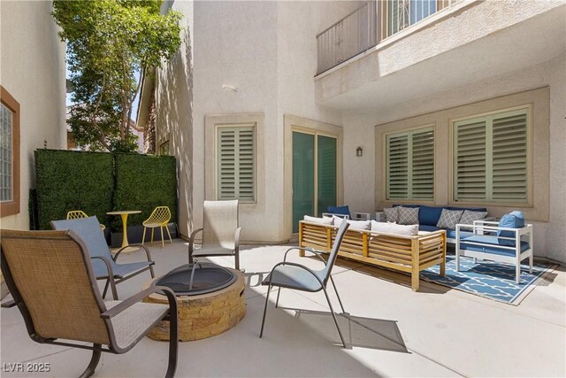 view of patio with an outdoor living space with a fire pit