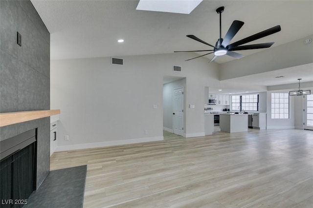 unfurnished living room with a tiled fireplace, visible vents, and baseboards