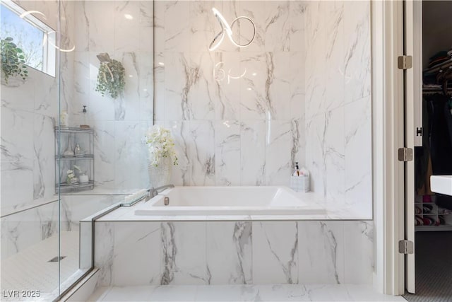 full bath with a walk in closet, a garden tub, and a marble finish shower