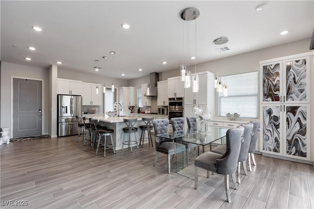 dining area with recessed lighting, a wealth of natural light, and light wood-style flooring
