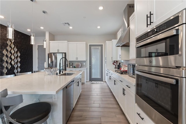 kitchen with a sink, visible vents, backsplash, light countertops, and appliances with stainless steel finishes