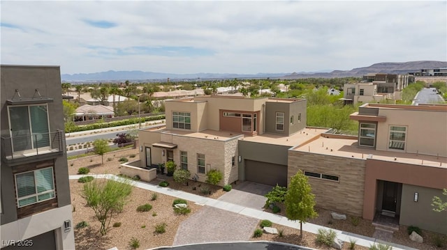 view of building exterior with driveway, a mountain view, a residential view, and a garage