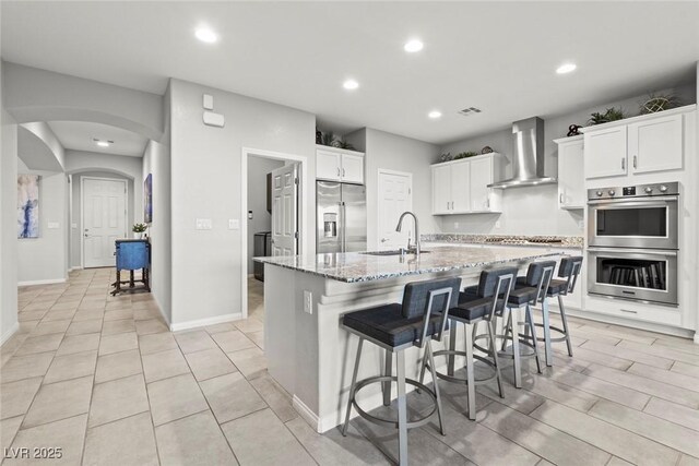 5852 Ireland Ridge Ct, Las Vegas, NV 89149 - kitchen with appliances with stainless steel finishes, wall chimney exhaust hood, a sink, recessed lighting, and light stone countertops