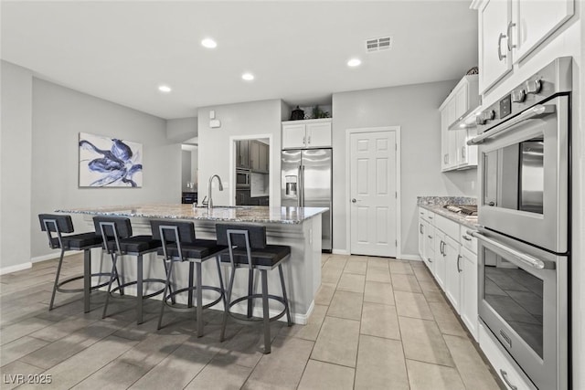5852 Ireland Ridge Ct, Las Vegas, NV 89149 - kitchen featuring stainless steel appliances, a kitchen island with sink, white cabinets, a breakfast bar area, and recessed lighting