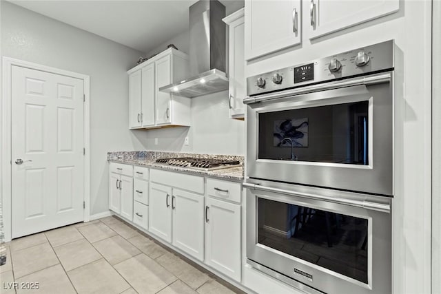 5852 Ireland Ridge Ct, Las Vegas, NV 89149 - kitchen with wall chimney range hood, appliances with stainless steel finishes, white cabinetry, light tile patterned floors, and light stone counters