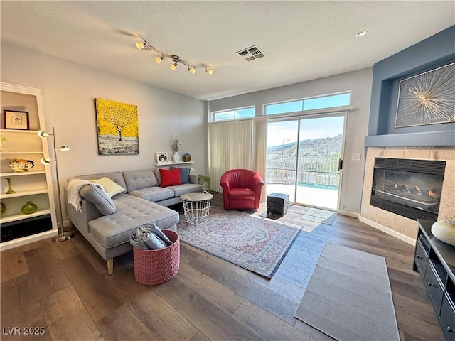 living room featuring a fireplace, wood finished floors, visible vents, and baseboards