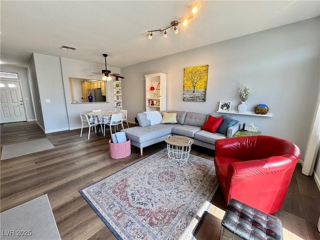 living room with wood finished floors, visible vents, baseboards, and ceiling fan