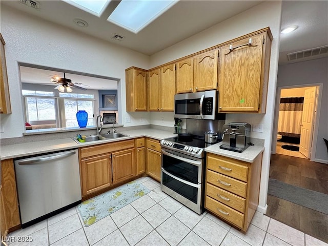 kitchen with stainless steel appliances, light countertops, visible vents, and a sink
