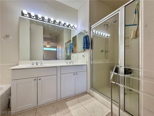 bathroom with a shower stall, a ceiling fan, a textured wall, and a sink